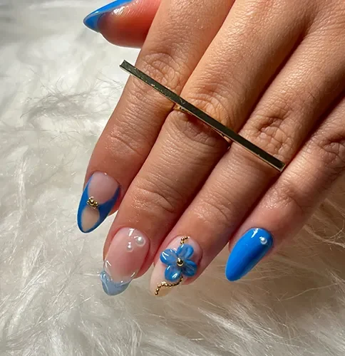 Unhas azuis com detalhes florais — trabalho de Geisla Souza